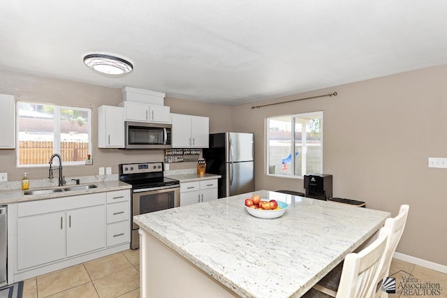 kitchen featuring plenty of natural light, a sink, appliances with stainless steel finishes, and light tile patterned flooring