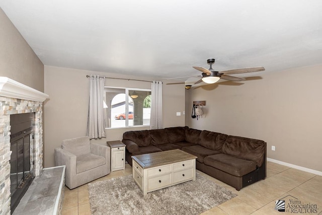 living area featuring light tile patterned floors, ceiling fan, and a glass covered fireplace