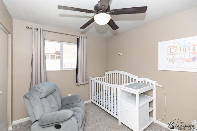 bedroom featuring baseboards, carpet, ceiling fan, and a nursery area