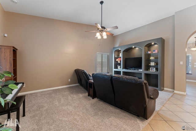 living room with baseboards, arched walkways, ceiling fan, and light tile patterned floors