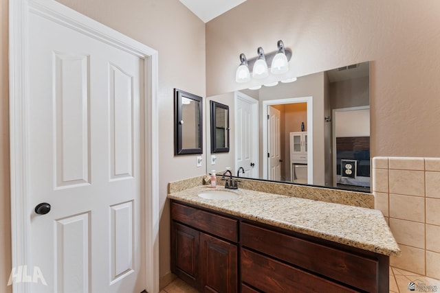 ensuite bathroom featuring vanity, tile patterned flooring, visible vents, and connected bathroom