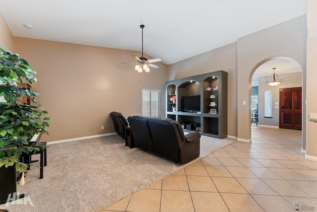 living area with lofted ceiling, baseboards, ceiling fan, arched walkways, and light tile patterned floors