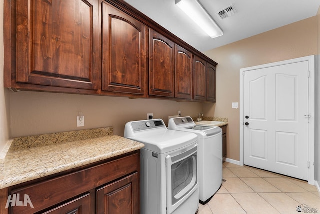 clothes washing area featuring visible vents, washing machine and dryer, baseboards, cabinet space, and light tile patterned floors