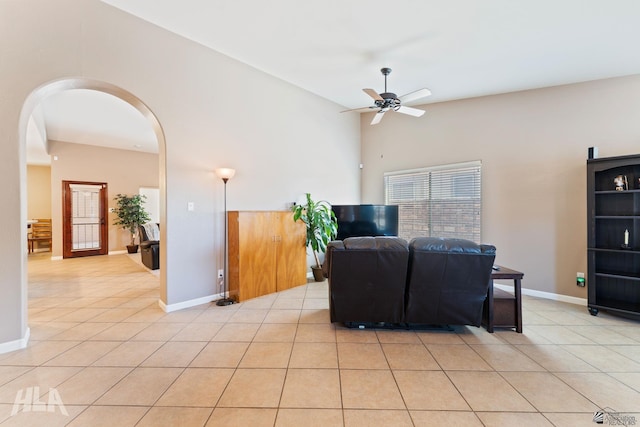 living room with baseboards, arched walkways, a ceiling fan, and light tile patterned flooring