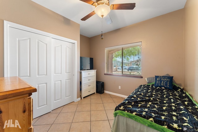 bedroom featuring light tile patterned floors, baseboards, ceiling fan, and a closet