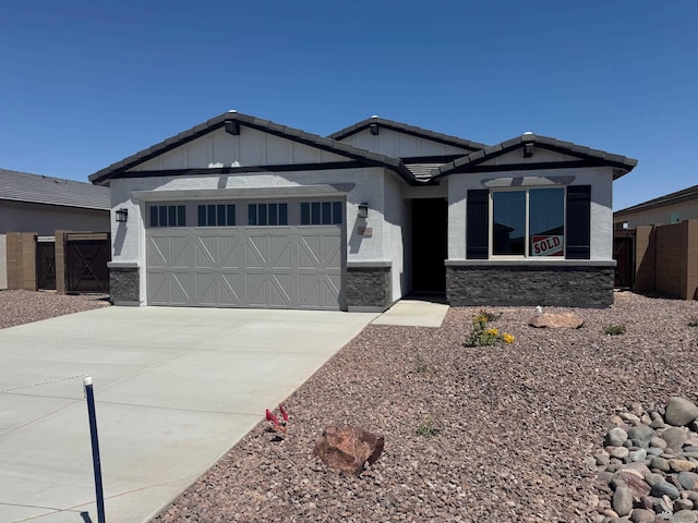 ranch-style house with fence, stone siding, board and batten siding, an attached garage, and driveway