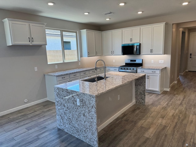 kitchen with a sink, stainless steel appliances, dark wood-style flooring, and white cabinetry