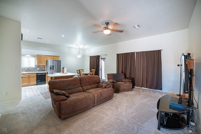 living room with ceiling fan, light colored carpet, and a textured ceiling