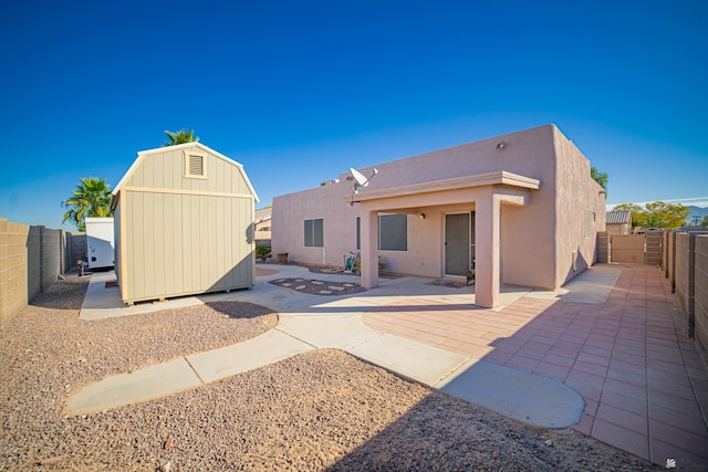 rear view of property with a storage unit and a patio