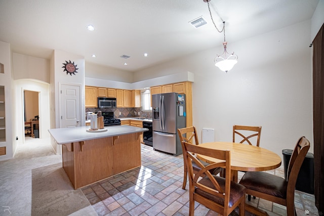 kitchen featuring pendant lighting, sink, decorative backsplash, a center island, and black appliances