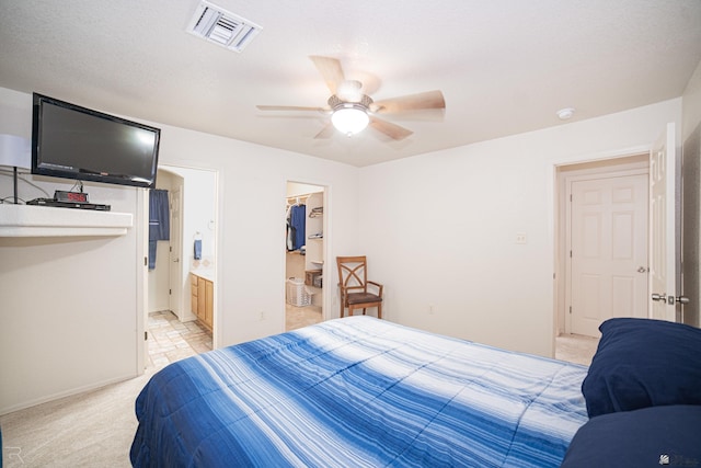 bedroom featuring ceiling fan, ensuite bathroom, light carpet, a spacious closet, and a closet