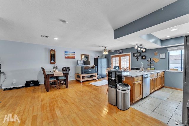 kitchen featuring a peninsula, a sink, light countertops, stainless steel dishwasher, and light wood-type flooring