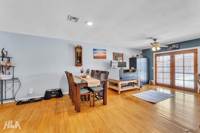 dining area with a textured ceiling, wood finished floors, visible vents, and baseboards