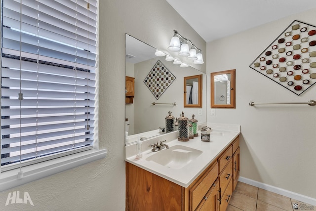 bathroom with baseboards, double vanity, a sink, and tile patterned floors