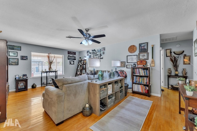 living room with visible vents, light wood-style flooring, a ceiling fan, a textured ceiling, and baseboards