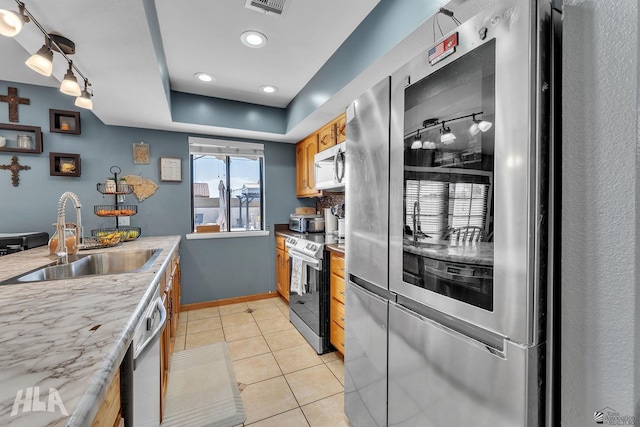 kitchen with baseboards, light countertops, stainless steel appliances, a sink, and light tile patterned flooring