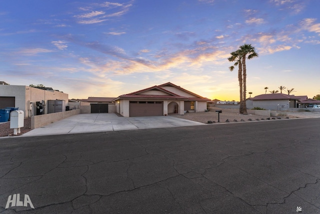 view of front of house with a garage, driveway, fence, and stucco siding