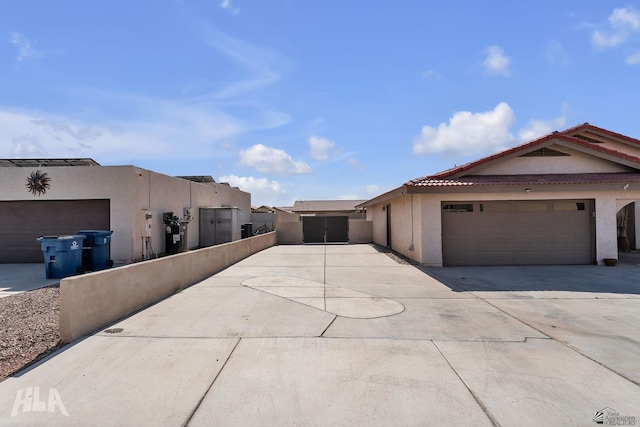 view of property exterior with driveway, a tiled roof, a gate, fence, and stucco siding