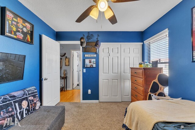 carpeted bedroom featuring a closet, ceiling fan, and a textured ceiling