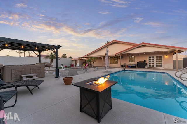 pool at dusk with a hot tub, a patio area, an outdoor fire pit, and a fenced in pool