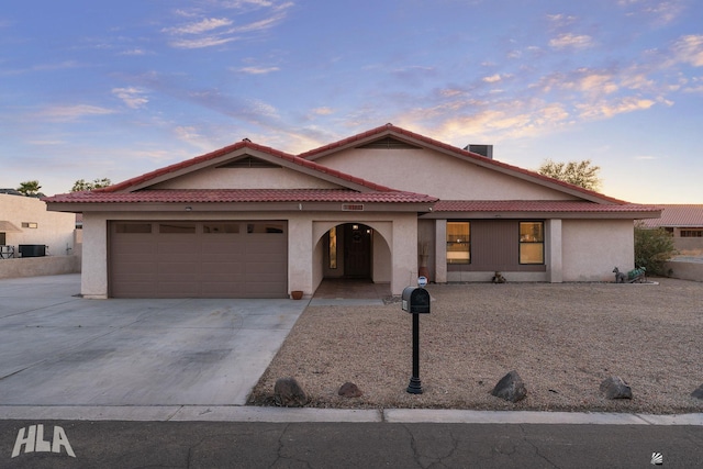 view of front facade featuring driveway, a tiled roof, an attached garage, and stucco siding