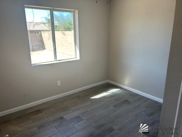 empty room featuring dark wood-type flooring and baseboards
