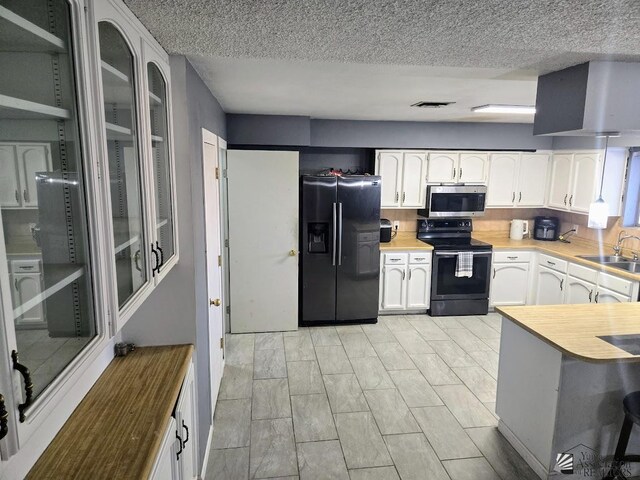 1957 Athens Ave, Yuma, AZ 85364 - kitchen featuring visible vents, range with electric stovetop, stainless steel microwave, white cabinets, and black fridge