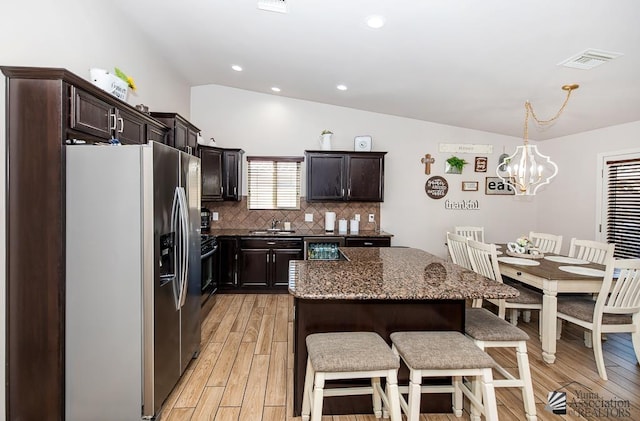10120 S Galaxy Ave, Yuma, AZ 85367 - kitchen with an inviting chandelier, a kitchen breakfast bar, light wood-type flooring, stainless steel refrigerator with ice dispenser, and vaulted ceiling