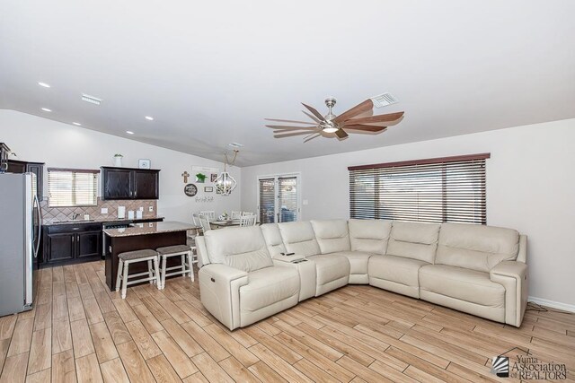 10120 S Galaxy Ave, Yuma, AZ 85367 - living room featuring visible vents, lofted ceiling, light wood finished floors, and ceiling fan with notable chandelier
