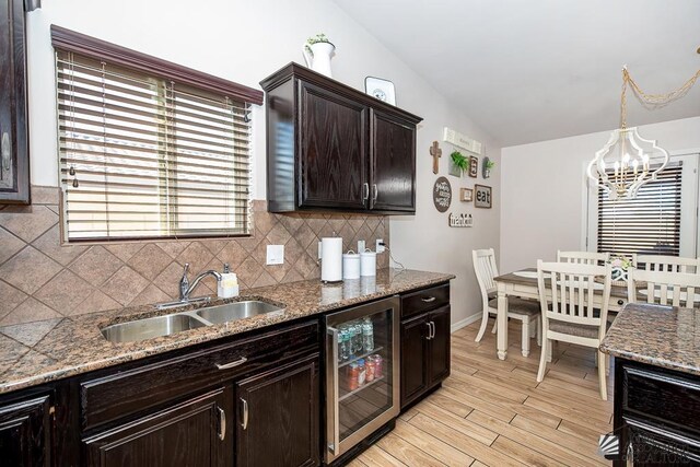 10120 S Galaxy Ave, Yuma, AZ 85367 - kitchen with dark brown cabinetry, a notable chandelier, a sink, wine cooler, and backsplash