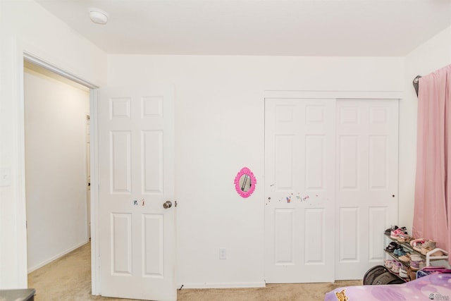 bedroom with light carpet, a closet, and baseboards