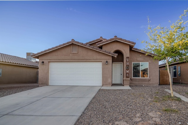 mediterranean / spanish house with an attached garage, stucco siding, concrete driveway, and a tile roof