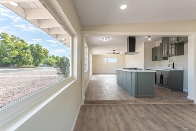 kitchen featuring a sink, stainless steel gas cooktop, light countertops, extractor fan, and baseboards