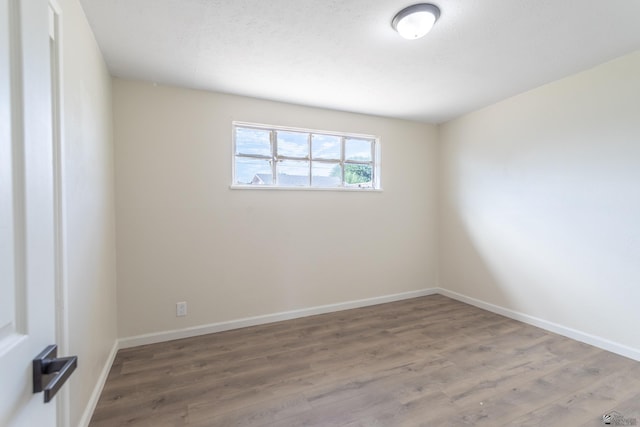 spare room featuring baseboards and wood finished floors