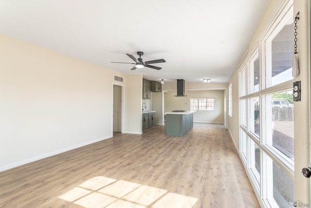 unfurnished living room featuring ceiling fan, visible vents, a sink, baseboards, and light wood finished floors