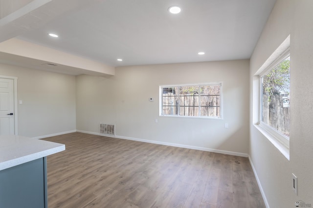 spare room with plenty of natural light, light wood finished floors, baseboards, and visible vents