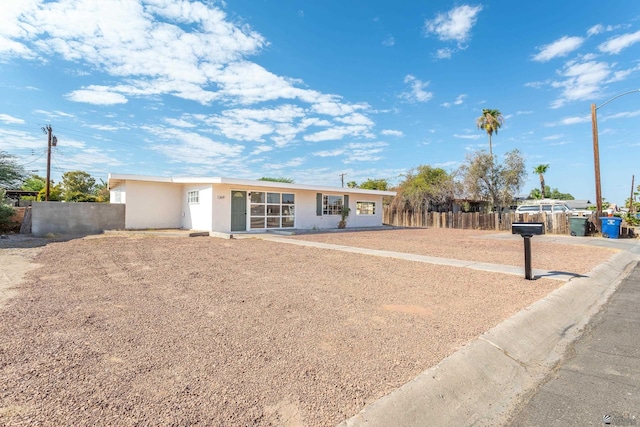 ranch-style house with fence and stucco siding