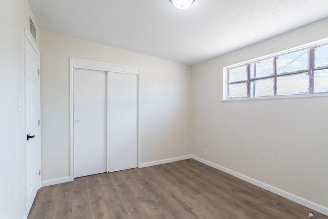 unfurnished bedroom featuring baseboards, a closet, and wood finished floors