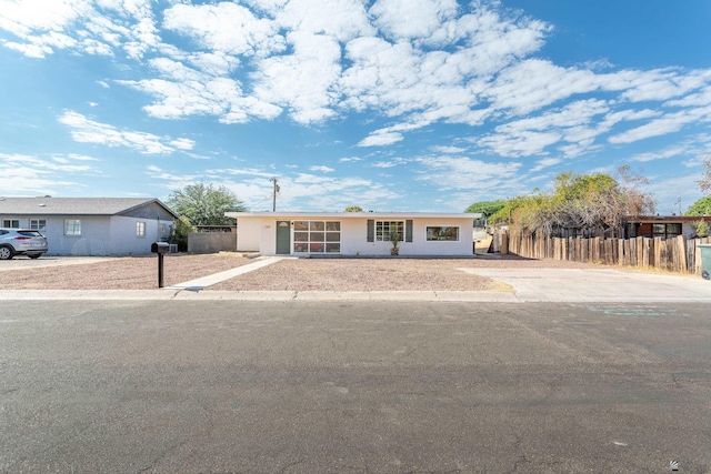 ranch-style house featuring stucco siding and fence