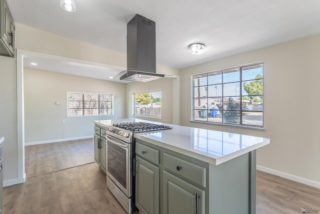 kitchen featuring island range hood, stainless steel range with gas cooktop, light countertops, a center island, and light wood-type flooring