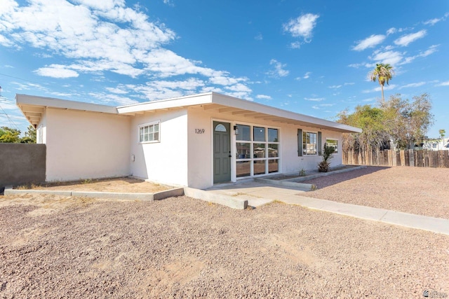 back of property with fence, heating fuel, and stucco siding