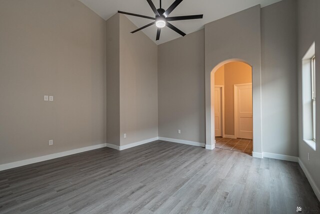 7972 E 34th Ln, Yuma, AZ 85365 - empty room with a ceiling fan, arched walkways, wood finished floors, high vaulted ceiling, and baseboards