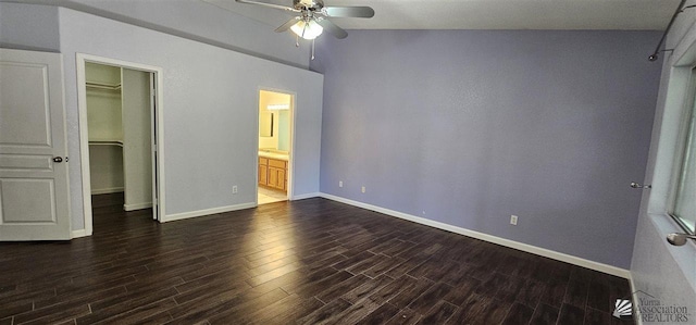 unfurnished bedroom featuring a closet, baseboards, dark wood-type flooring, a spacious closet, and ensuite bath
