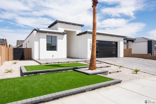 view of front facade with driveway, a front yard, a garage, fence, and stucco siding