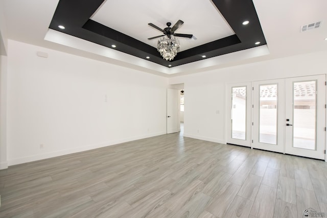 spare room featuring ceiling fan, visible vents, baseboards, light wood-style floors, and a tray ceiling
