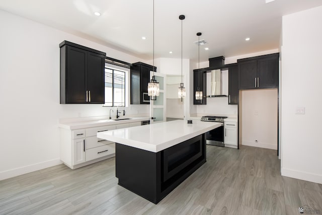 kitchen with stainless steel stove, light countertops, dark cabinetry, and light wood-style flooring