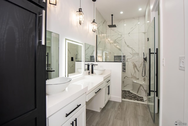 bathroom with a sink, a marble finish shower, and double vanity