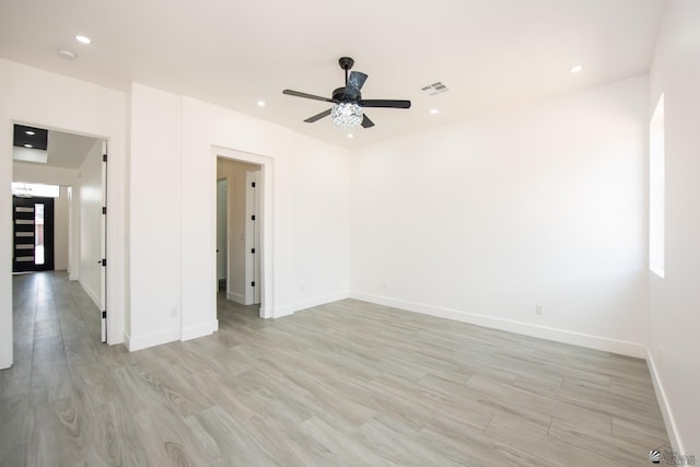 empty room featuring visible vents, light wood finished floors, ceiling fan, and baseboards