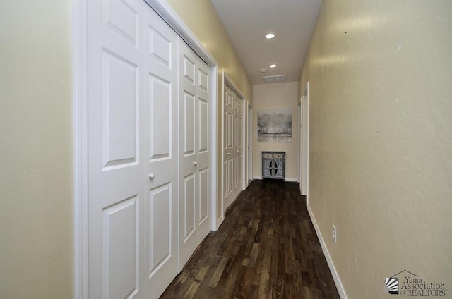 hall featuring dark wood-type flooring, recessed lighting, and baseboards