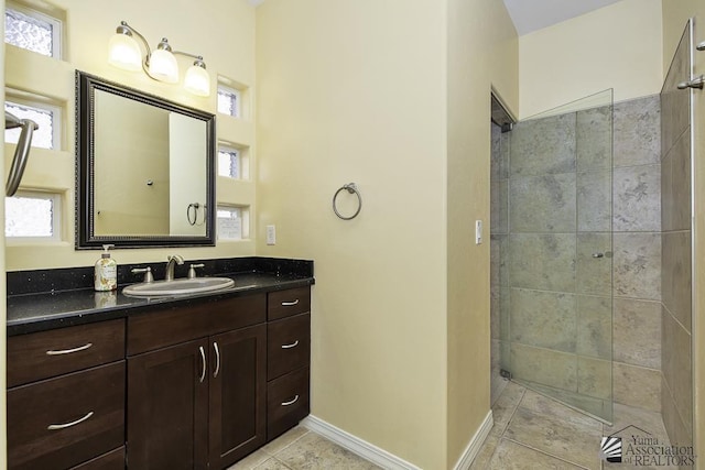 bathroom featuring tiled shower, tile patterned floors, vanity, and baseboards